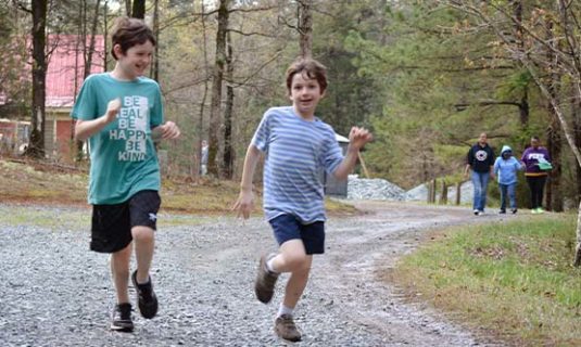 two campers running down the gravel path at Camp Royall