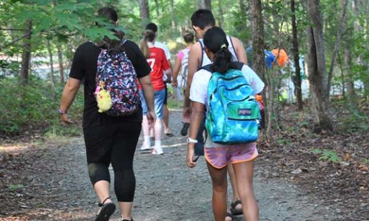 Campers and counselors hike into the woods of Camp Royall