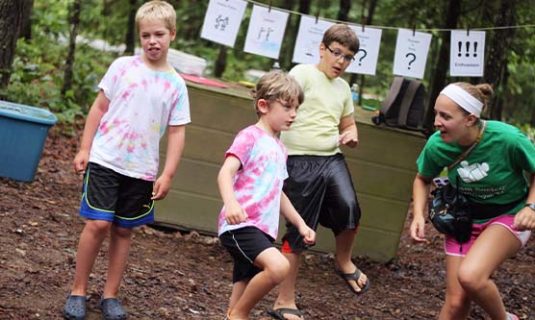 Three campers and a counselor play a game in nature.