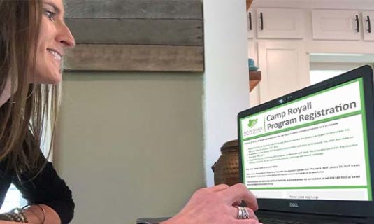 A parent at her computer, looking over the Camp Royall Registration form.