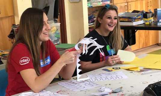 College students helping with arts and crafts at camp.