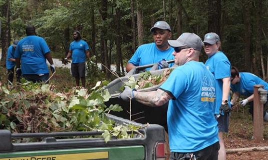 A group of volunteers cleaning up brush and debris at camp.