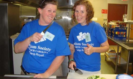 Camp staff smiling while prepping lunch in the camp kitchen.