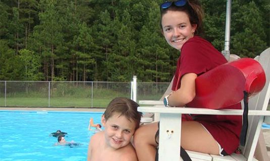 A lifeguard at Camp Royall's pool, poses with a camper.