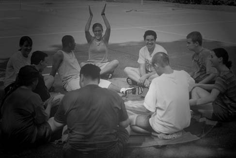 Teens and their counselor sitting in a circle and playing a game.