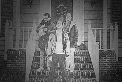 A group of young men pose for a dramatic picture on the front steps of a home.