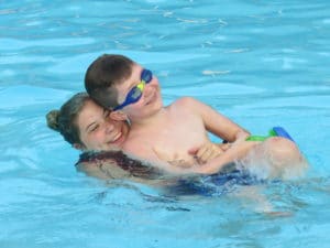 John and a counselor in the pool at Camp Royall, an autism summer camp