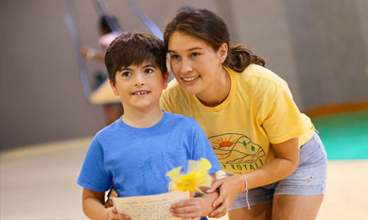 Camper and a Counselor smiling in the gym