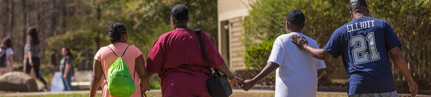 A happy family walks outside on a sunny day, while holding hands.