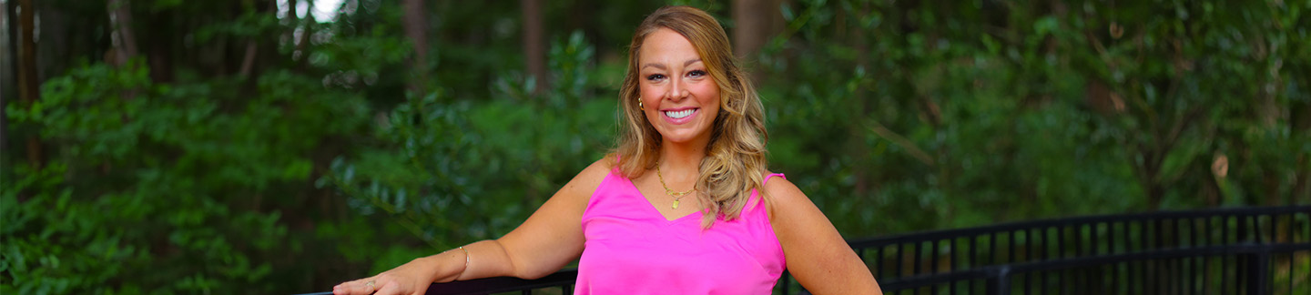 Clinical Director, Whitney Sukonick, smiles for the camera in front of a wooded background.