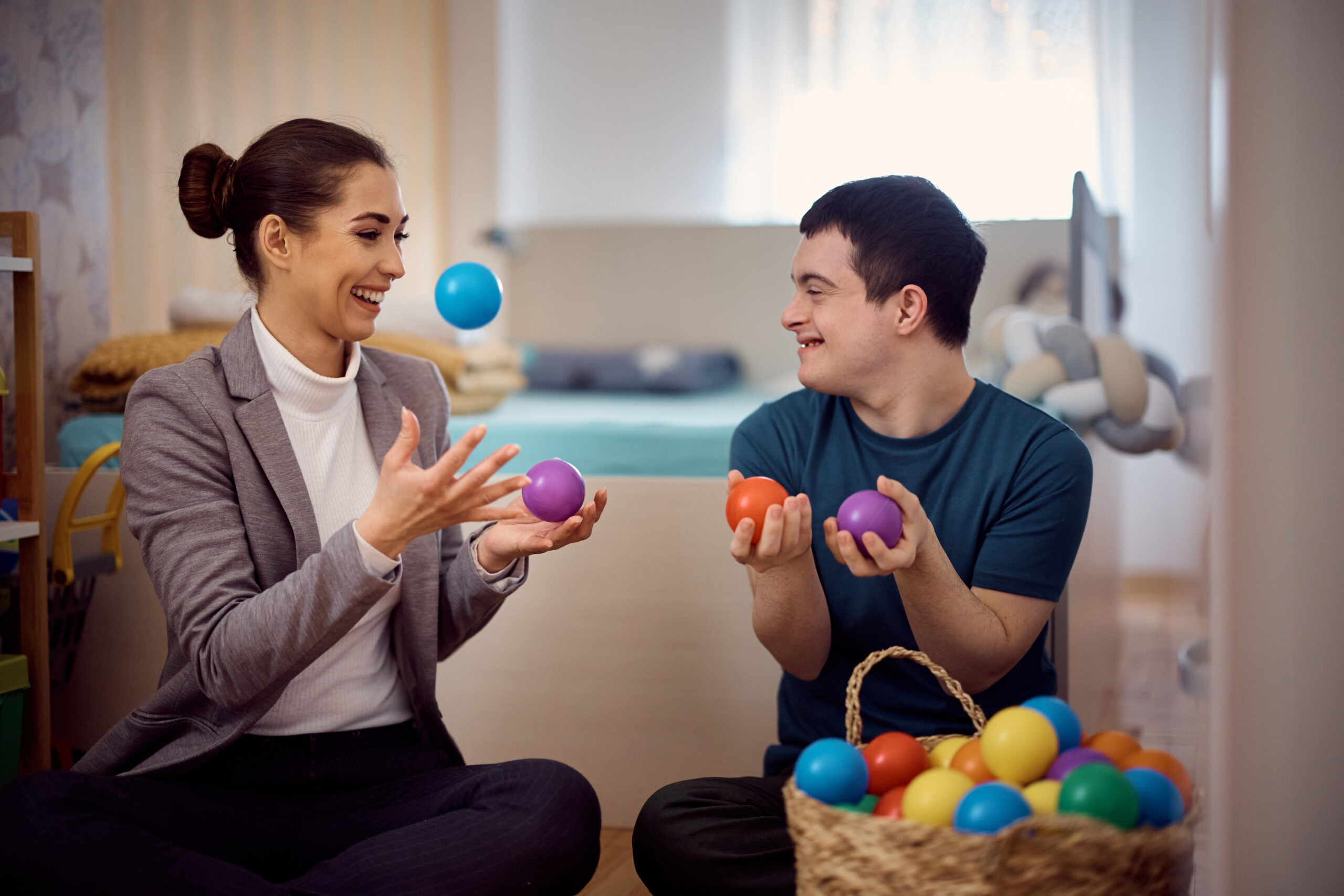 Playful man with down syndrome and his therapist having fun with plastic ball at home. caregivers autistic adults