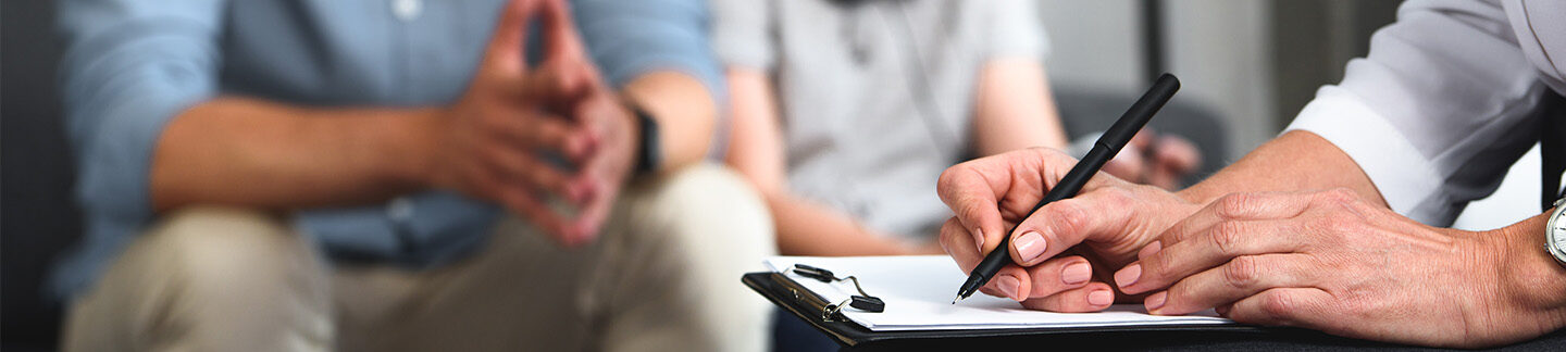 Hands of a therapist while taking notes during an autism diagnosis.