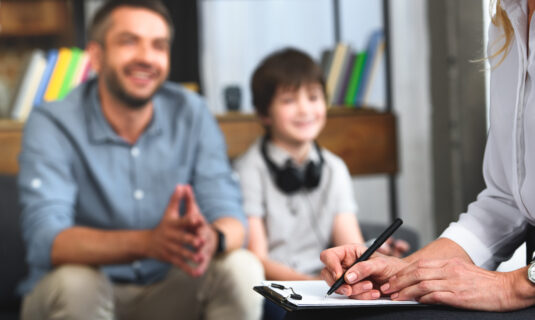 A father and son speaking with a family therapist.