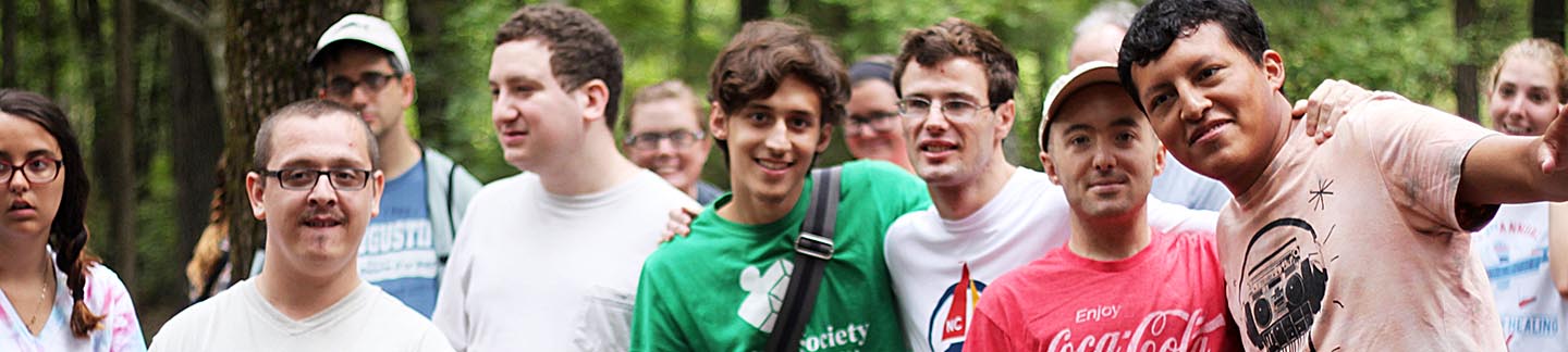 A group of teens, arm-in-arm, posing for a picture at camp.