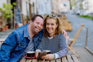 A portrait of happy young man with his caregiver sitting on a community outing.