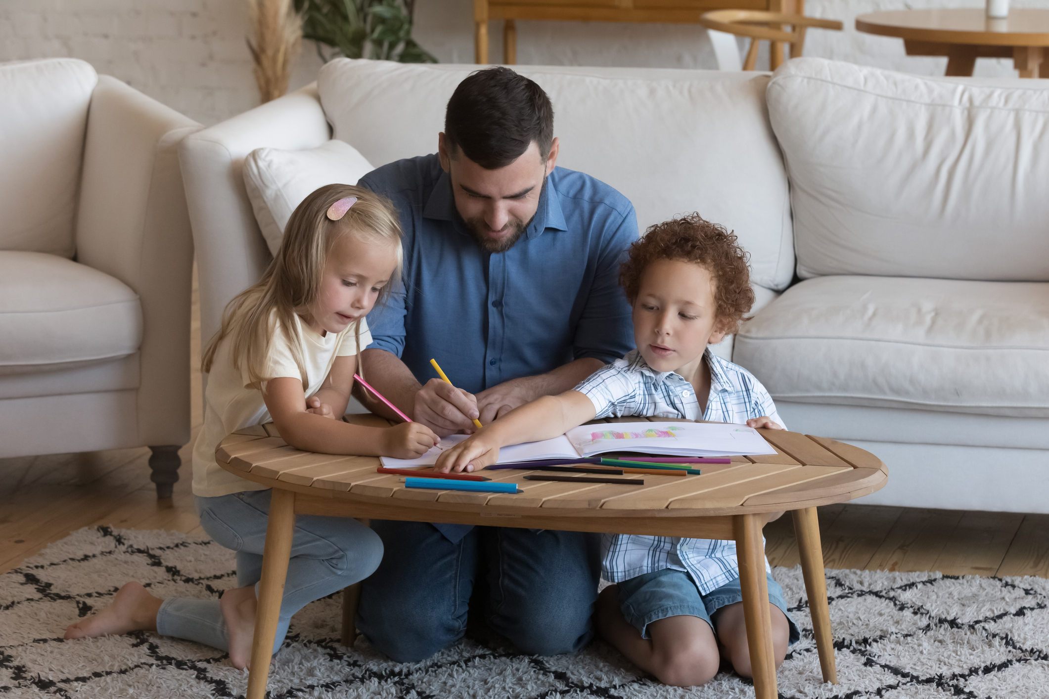 Father and siblings drawing pictures with pencils