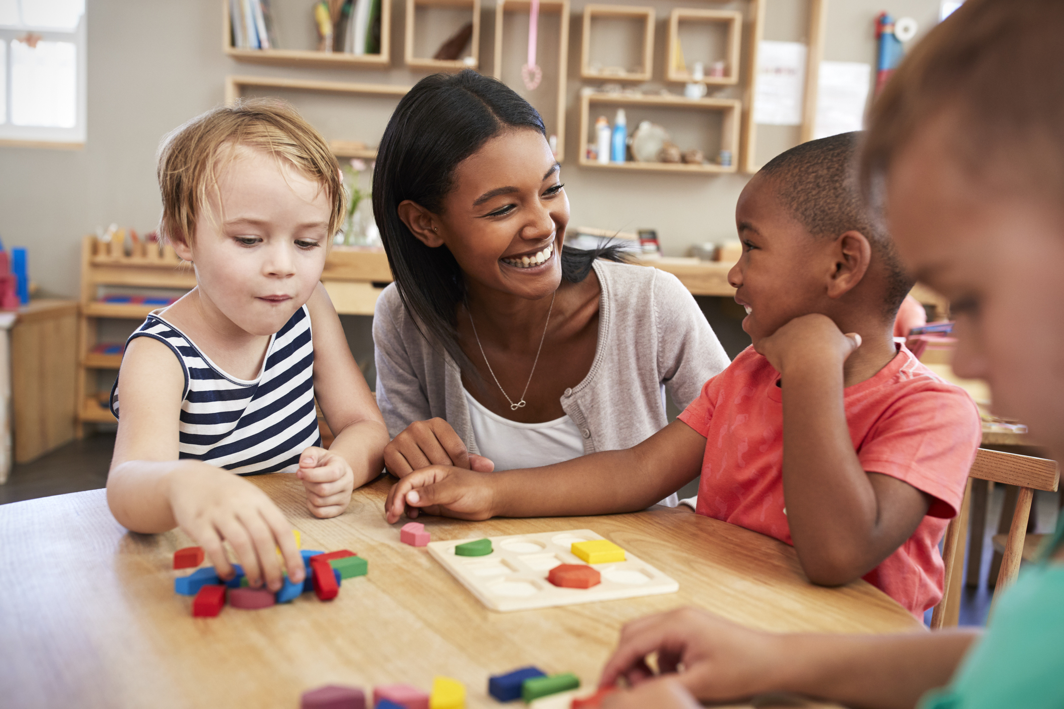 A teacher smiles with her young students in the classroom.