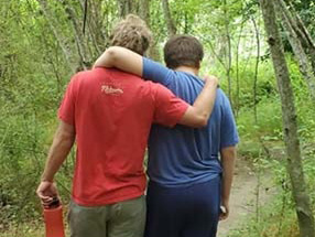 Two friends walk in the woods.
