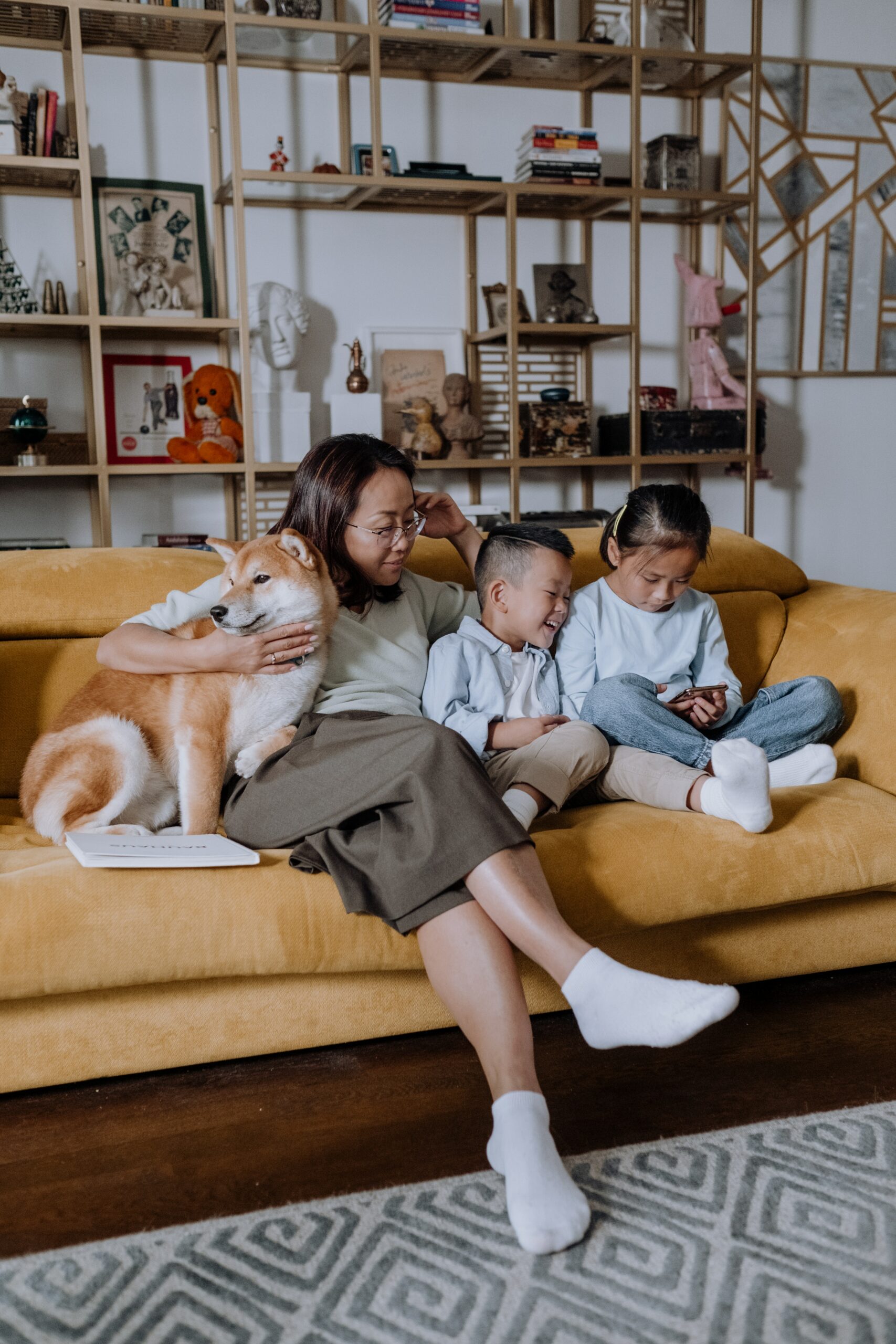 A mother and her two children sit on the sofa with their dog.