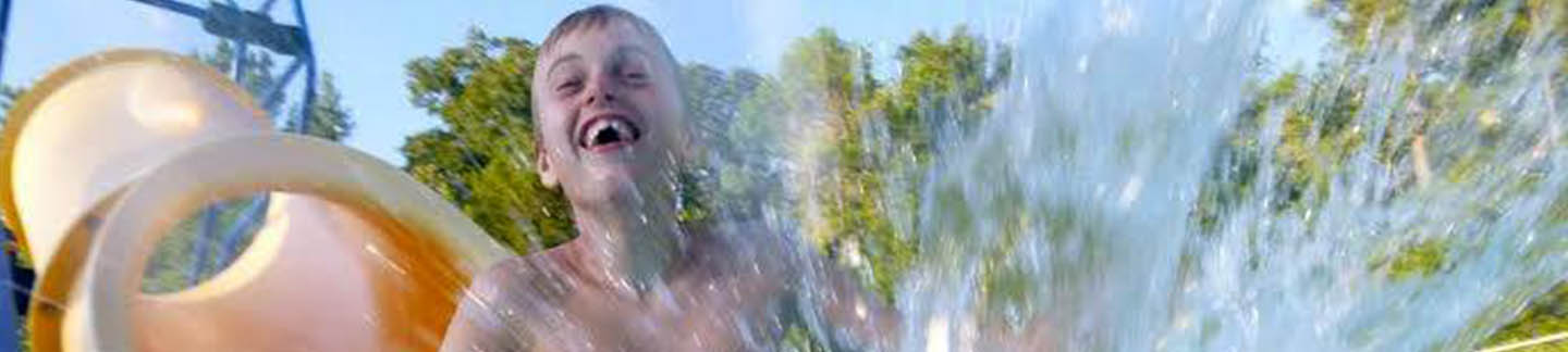 A photo of a young boy splashing into a pool